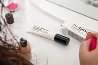 Hand with beauty blender next to MAC Studio Radiance Illuminating Primer