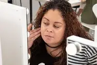 Person rubbing Milk Makeup Hydro Grip Hydrating Makeup Primer onto their face in mirror