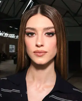 model wears winged eyeliner look and peach nude lipstick