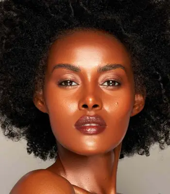 model wears glowing makeup look with dark brown lipstick