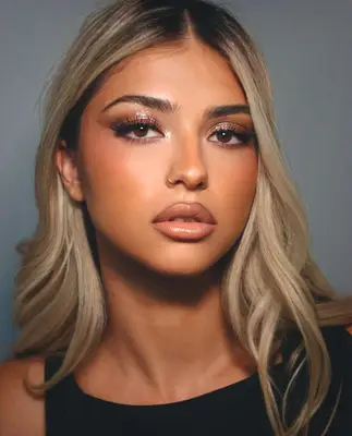 model is wearing sparkly bronze eyeshadow and visible winged liner