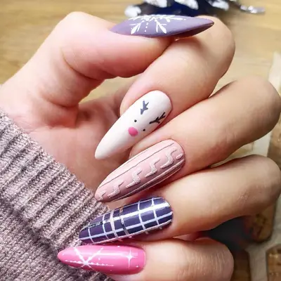 Pink, purple, and white manicure with snowflakes, a reindeer, and sweater nail designs