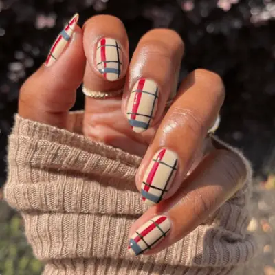 woman with red and tan sweater nail design