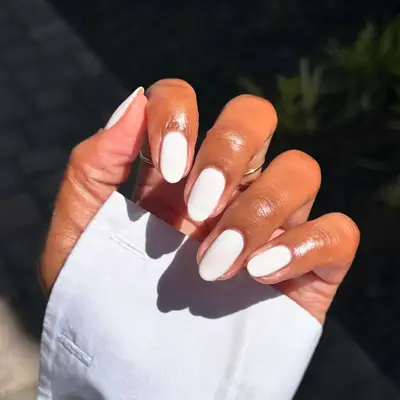 Hand with neatly manicured nails painted white 