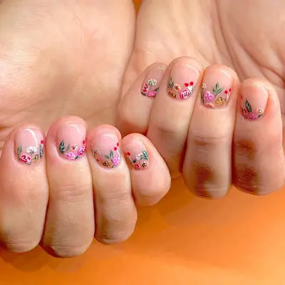 A close-up of hands displaying nail art with small floral designs