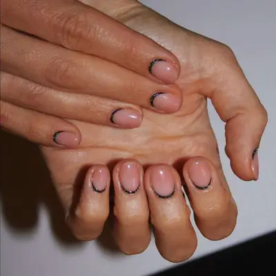 Hands with reverse French manicure showing black outlines at the nail base