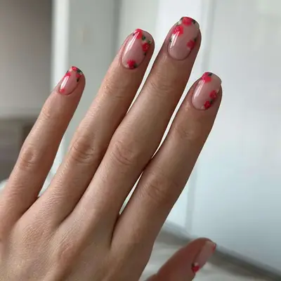 Hand with nails decorated with red floral designs