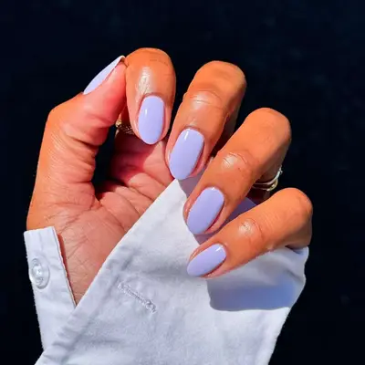 A closeup of a hand with lavender-colored manicured nails