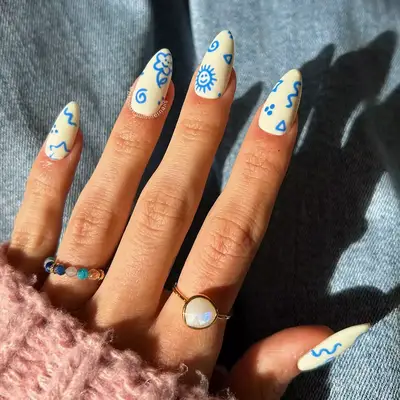 a doodle manicure with a white base and blue drawings