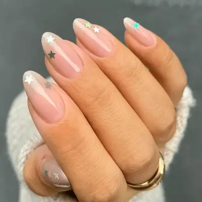 Hand with nude manicured nails, featuring star designs