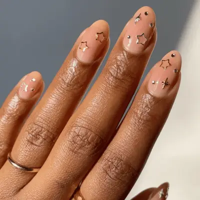Hand with polished natural nails decorated with small metal stars and studs