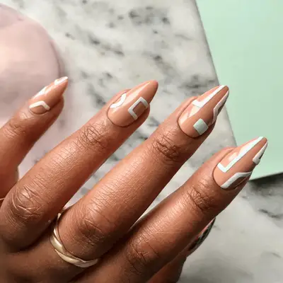 A hand displaying nails adorned with a geometric design