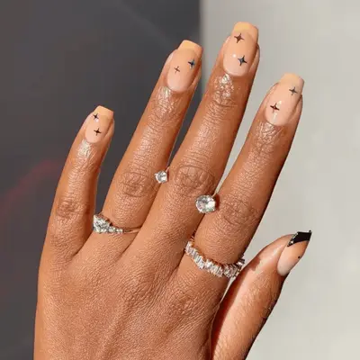 Hand wearing multiple rings with a star design on the nails