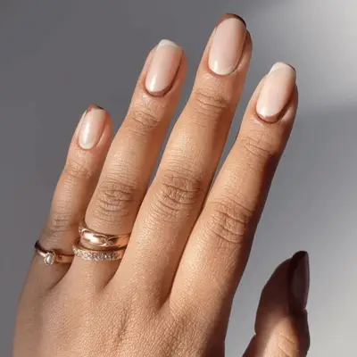 A hand displaying well-manicured nails and rings on the fingers