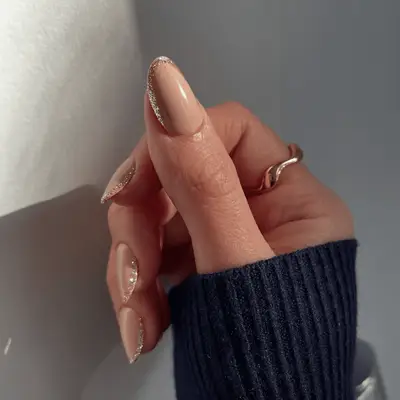 A hand with manicured nails and a ring, the nails have a glitter accent trim