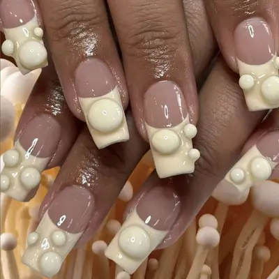 An off-wihite manicure with 3D accents on the tips