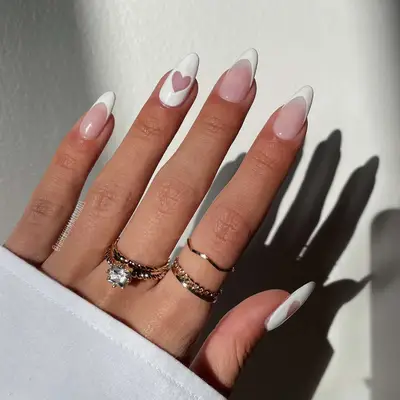 A white French manicure with white cutout heart accent nails