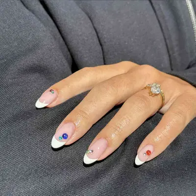 A classic white French manicure with gem accents