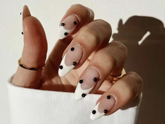 A white French manicure with black studs
