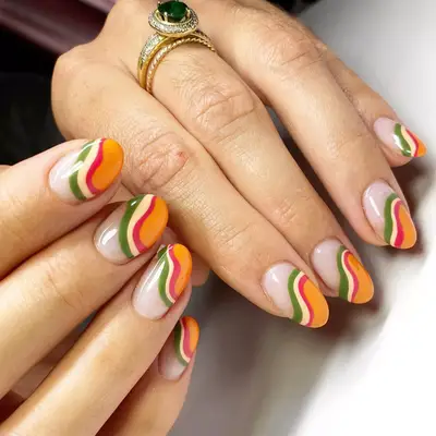 close up of nails painted in swirly design with shades of olive green, orange, red