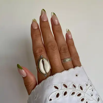 close up of nails painted in unique french tips with green and white accents