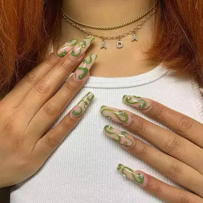 close up of nails painted in olive green swirls with light pink background