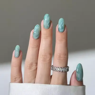a mint green manicure in a marble design