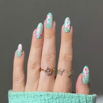 a mint green manicure topped with floral designs and dewdrops