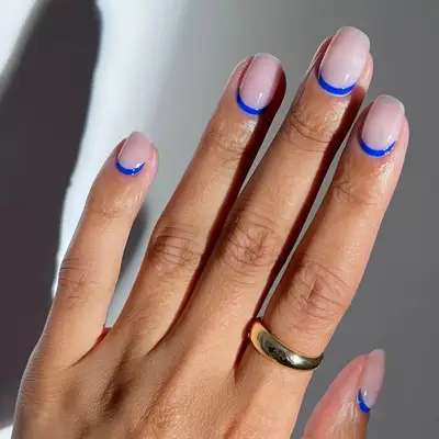 Neutral nails with royal blue cuticle design