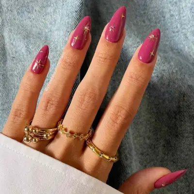 Berry-colored manicure with gold chrome stars.
