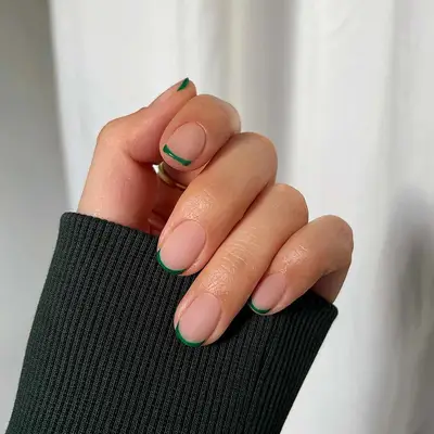 A short French manicure with a matte base and green tips