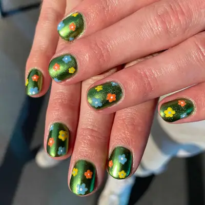 Close up of a metallic green manicure with retro flowers