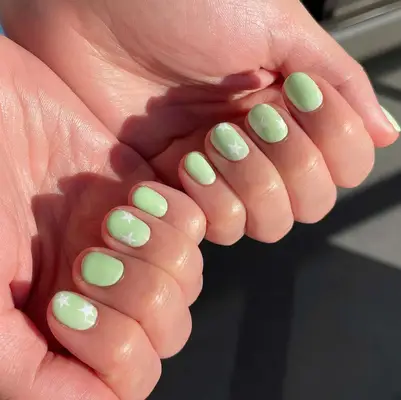 A short pistachio-green manicure with white stars