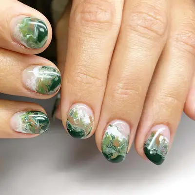 Close up of a short marbled green manicure 