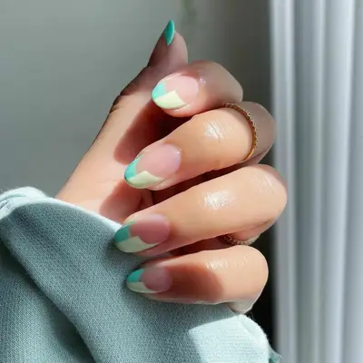 Close up of a split-tip French manicure in pastel shades of green