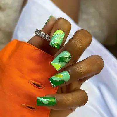 A short, square manicure with green squiggle designs