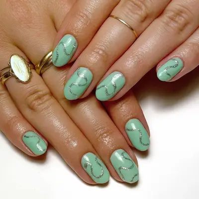 A pale green short mani with silver glitter swirls