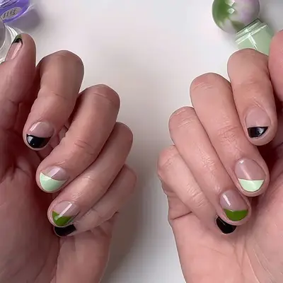 A short negative space manicure in pistachio, hunter green, and black