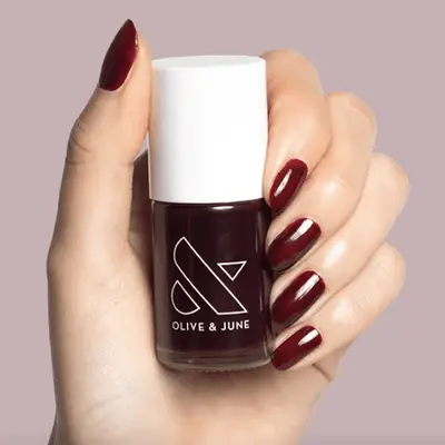 Bottle of metallic rose gold nail polish on a white background.