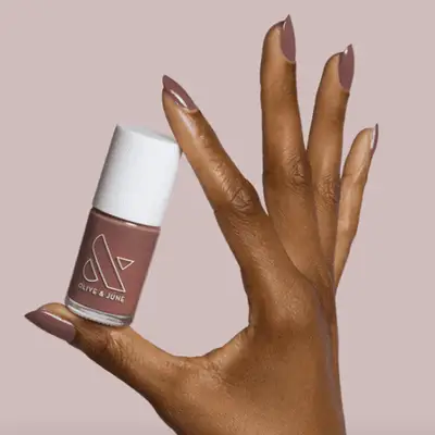 Bottle of berry nail polish on a white background with a black lid.