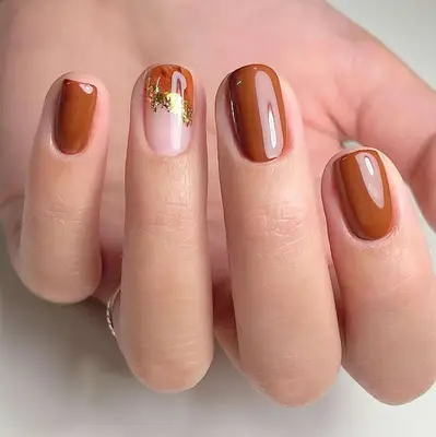 Close up of a brown manicure with one gold foil accent nail