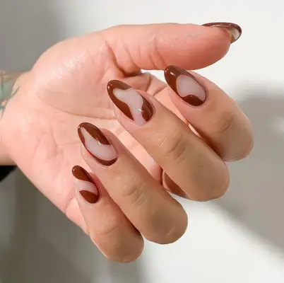 Close up of a brown manicure featuring negative space nail art