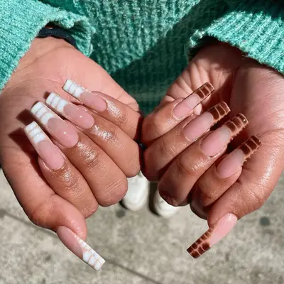 Close up of a manicure with two fingers polished in brown and two fingers polished half black, half brown