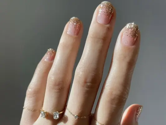 Close up of a glittery ombre French nail look