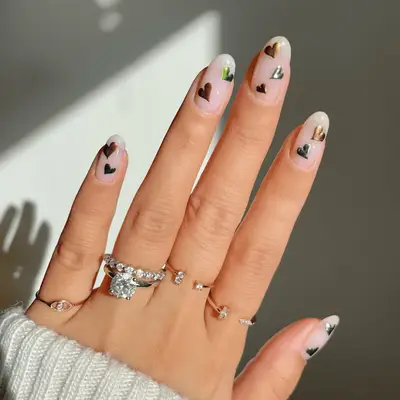 Nude nails with heart art in multicolor chrome. 