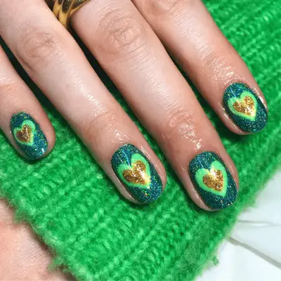 Blue and green glitter nails with gold heart details in the center.