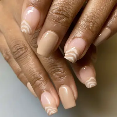 tan manicure with white swirl designs