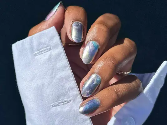 Close up of a hand with a shiny chrome manicure and perfectly clean cuticles