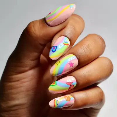 Close-up of manicure with pastel rainbow designs and heart, rainbow, smiley face, butterfly, and star stickers