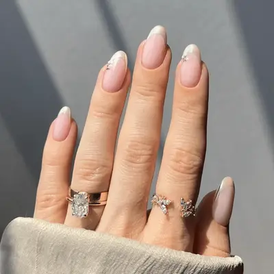 Almond shaped blush-tone nails with vanilla chrome french tips and floral accents